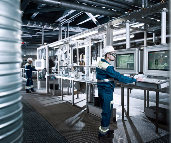 A worker wearing safety equipment uses a computer in an industrial
environment